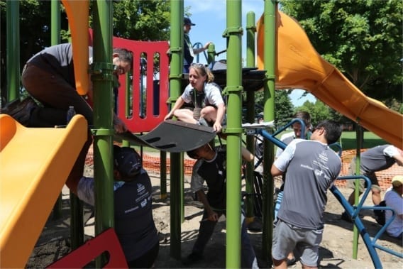 people working together in an urban park to build a playground for children