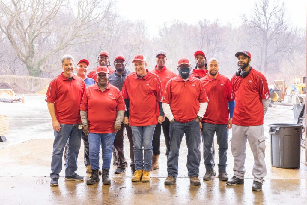 A group of staff in red shirts posing at a recycling center