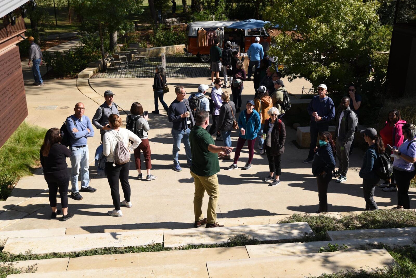 Park Study Tour attendees listening to a tour leader in a park plaza
