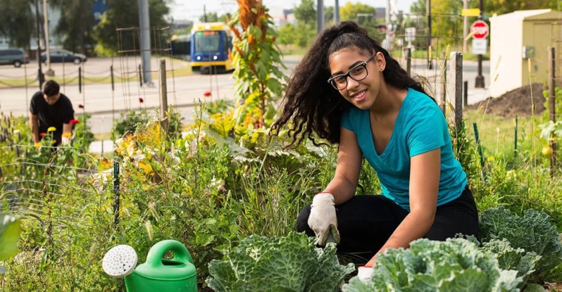 A young woman gardening in an urban food forest