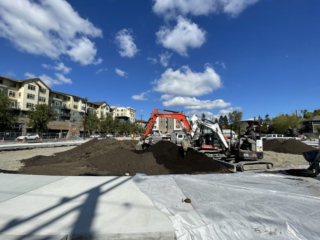 An excavator moving mounds of dirt at a new park