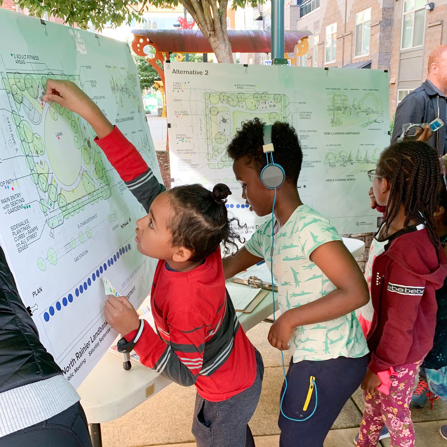 Three older kids interacting with poster plans of a new park