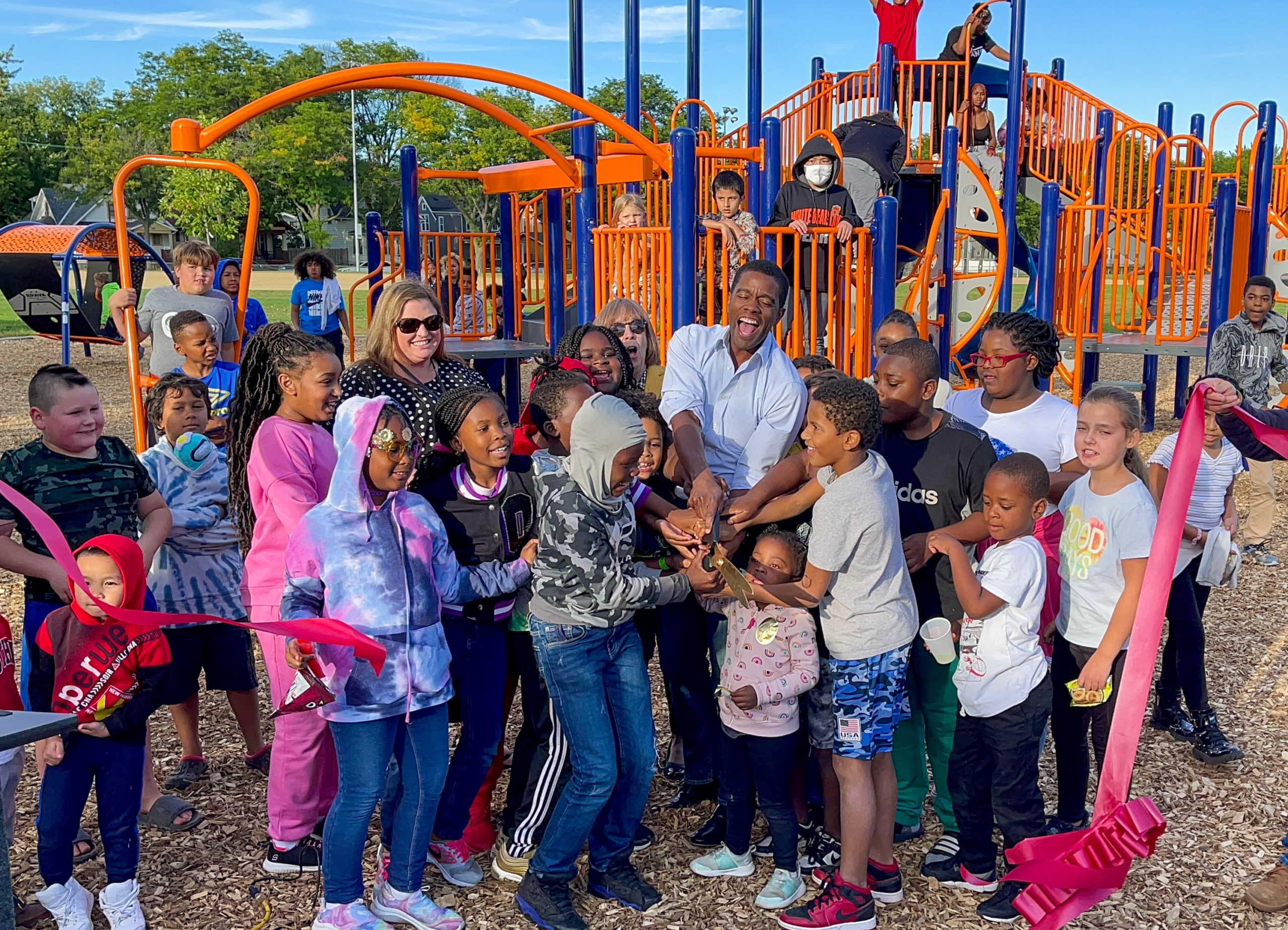 The St. Paul Mayor and a group of kids cutting a ribbon at a new park