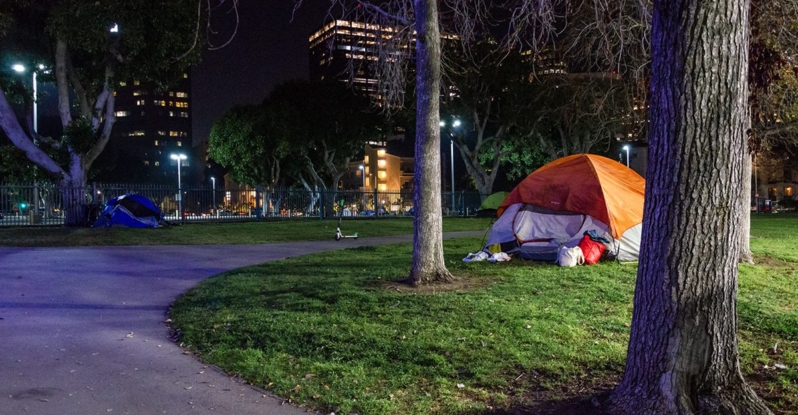 A tent for an unhoused person at night in a city park