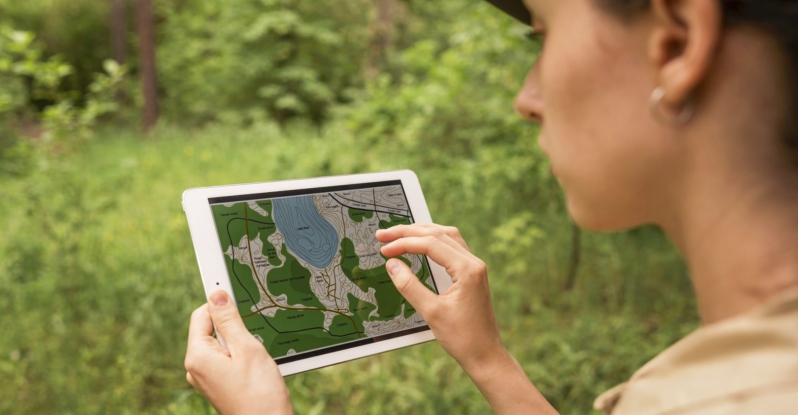 A woman holding an iPad showing topographic map of a park