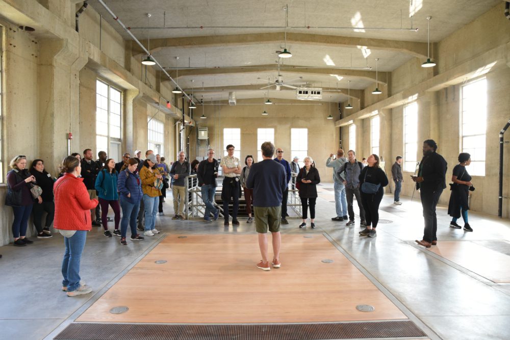 Group of people watching a man perform inside a large concrete structure.
