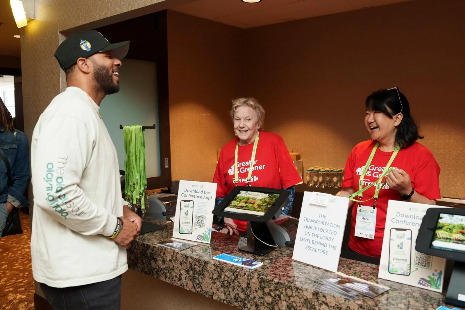 A man and two women smiling and laughing at a conference registration desk