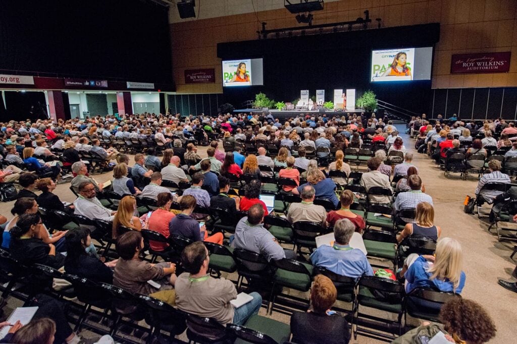 A large crowd listening to a person speak in an event hall