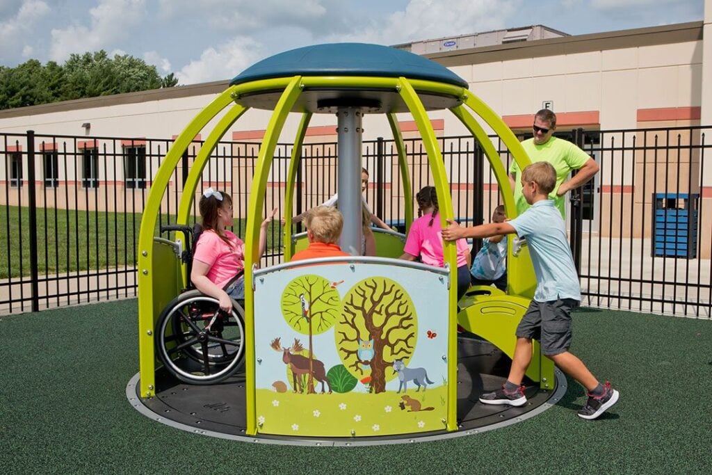 Children playing in an accessible, wildlife-themed merry-go-round