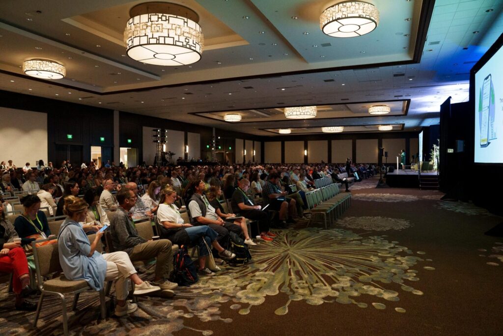 A large group of people listening to a speaker in an event hall