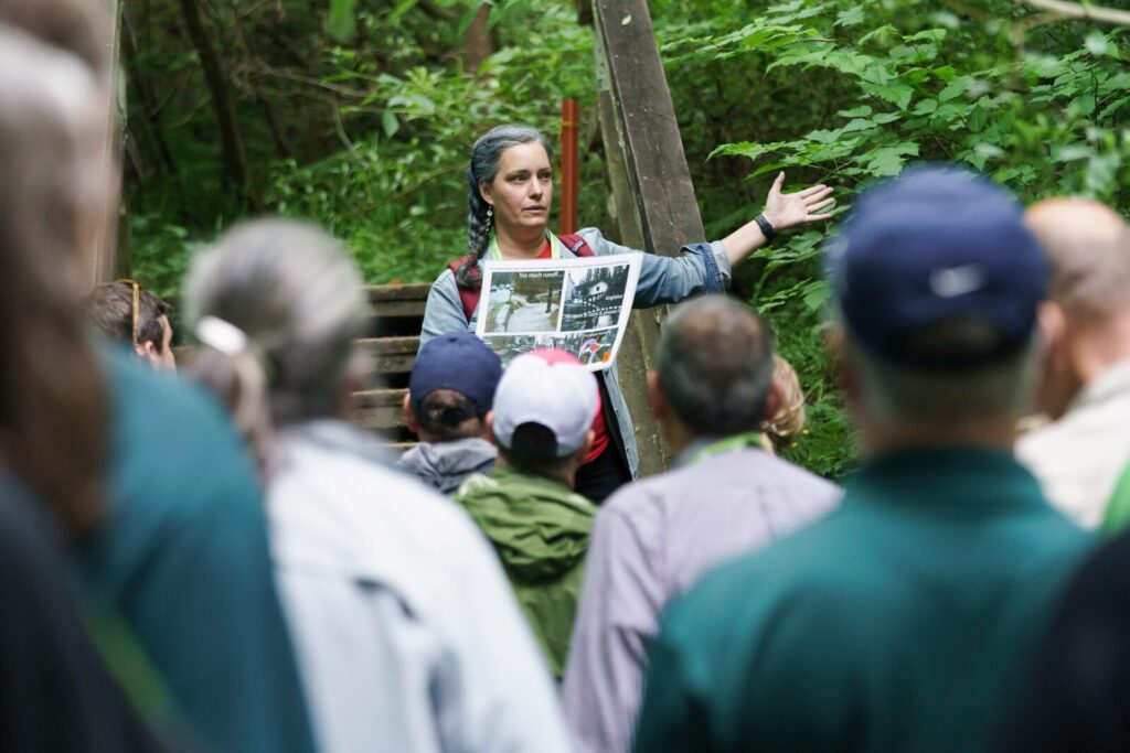 A woman speaking to a group of people in a park
