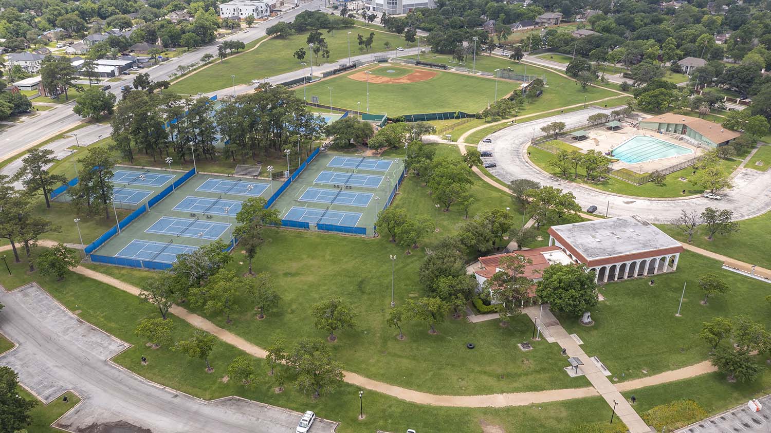 A park from overhead showing trees, a pool, tennis courts, baseball field, and a pavillion