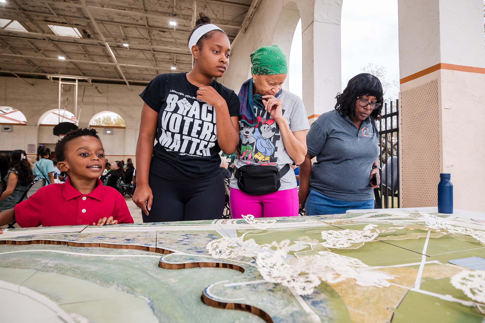 Three woman and a child looking over a 3D miniature plan of a park