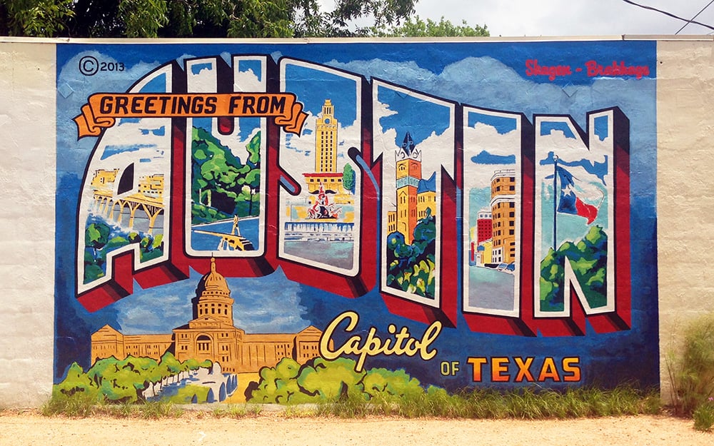 A mural with the word "Greetings from Austin: Capitol of Texas" with Austin, Texas iconography