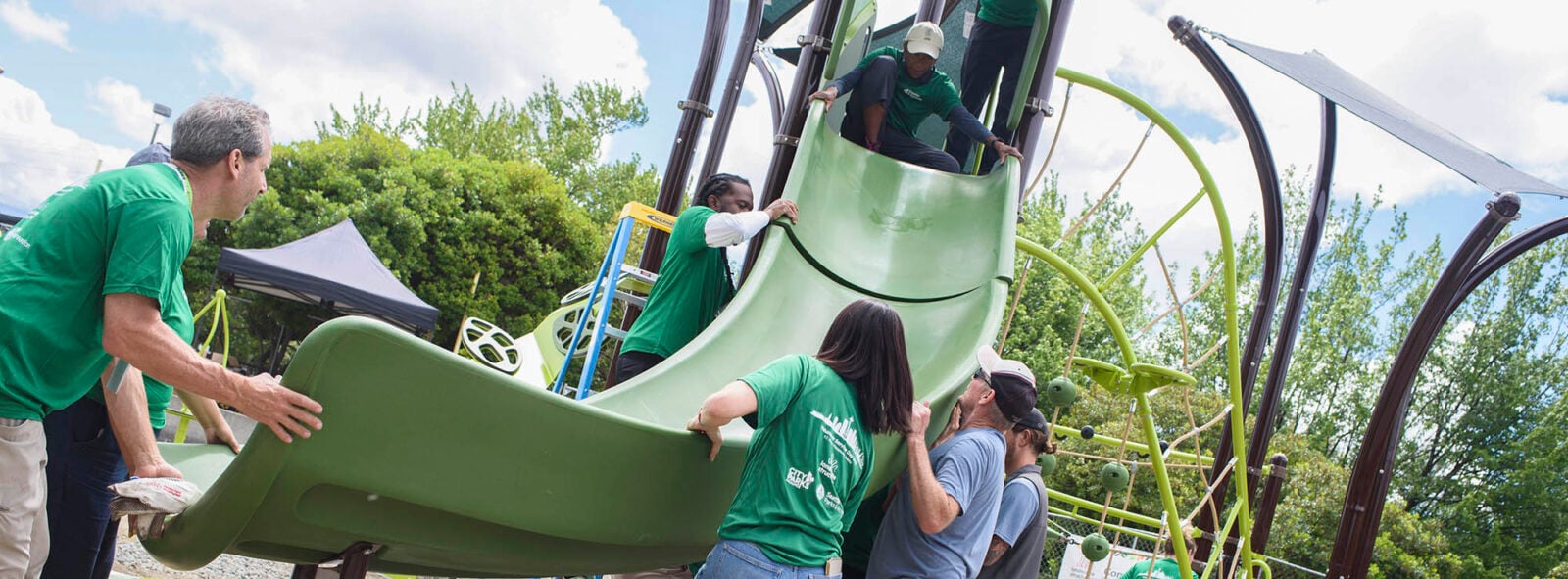A group of people lifting the bottom of a slide to secure it in to a new playground