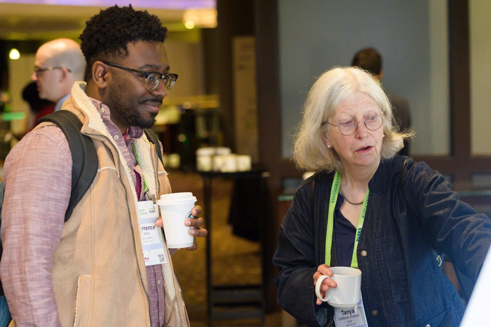 A man and a woman in conversation pointing to a poster board