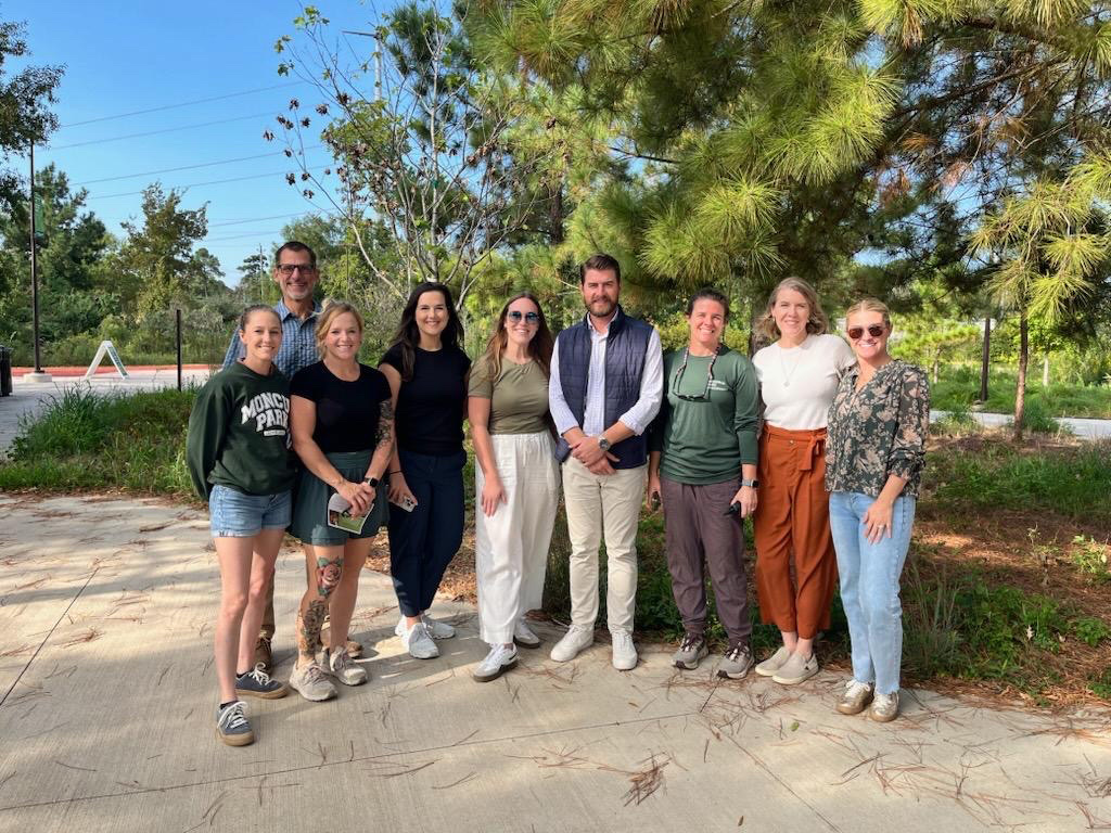 A group of people posing in a lush, green park