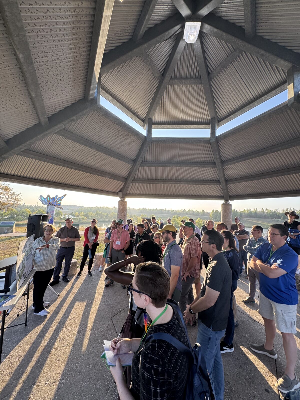 A tour group listening to a guide under a large gazebo