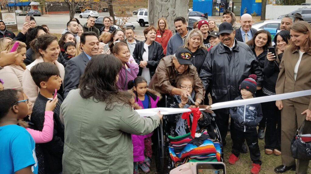 A large group of community members smiling as a ribbon is cut