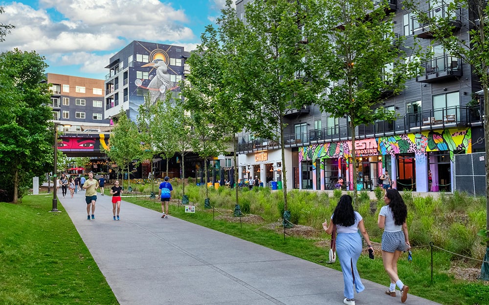 Pedestrians walking and running down a paved walkway in a city park