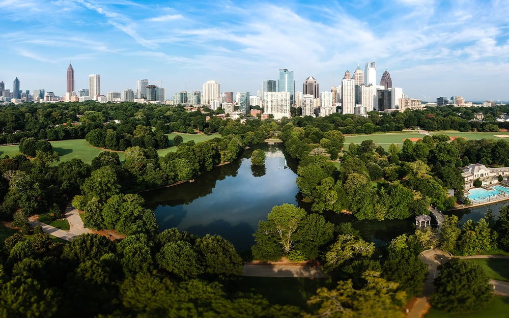 The Atlanta skyline and lush city park with a large lake and lush trees