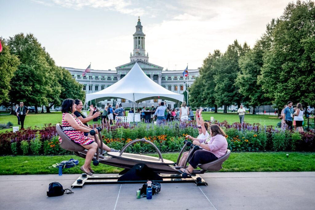 Women on an adult-sized see-saw at an outdoor reception
