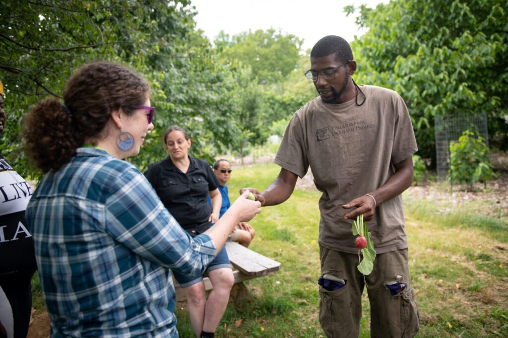 A man handing a woman a vegetable in a garden