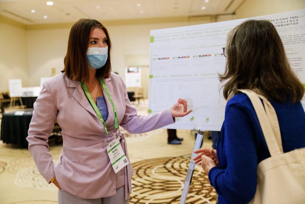 Two woman speaking next to a research poster board