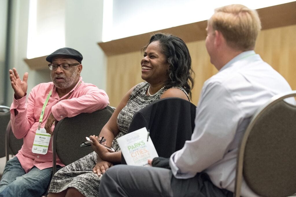 A woman and two men in chairs having a conversation