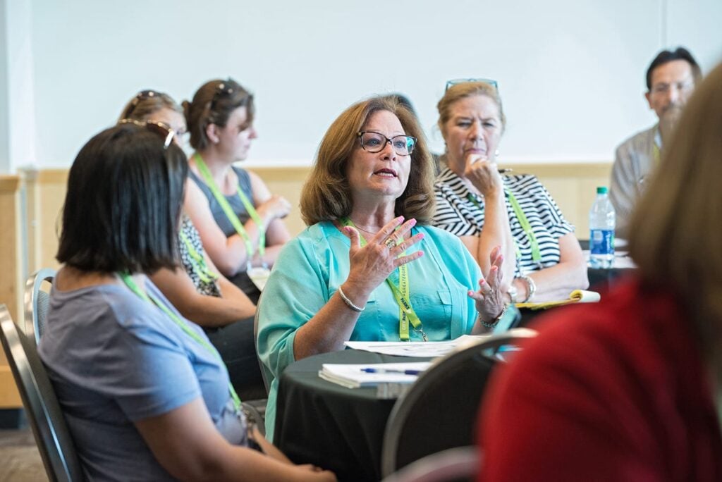 A woman at a table speaking to a group