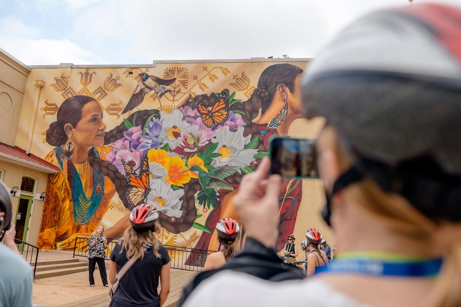 A bike rider taking a picture of public art depicting Native American women