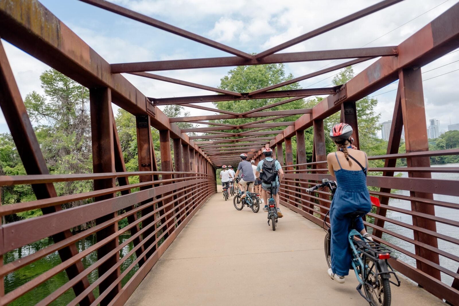 Bike riders cycling through a metal bridge