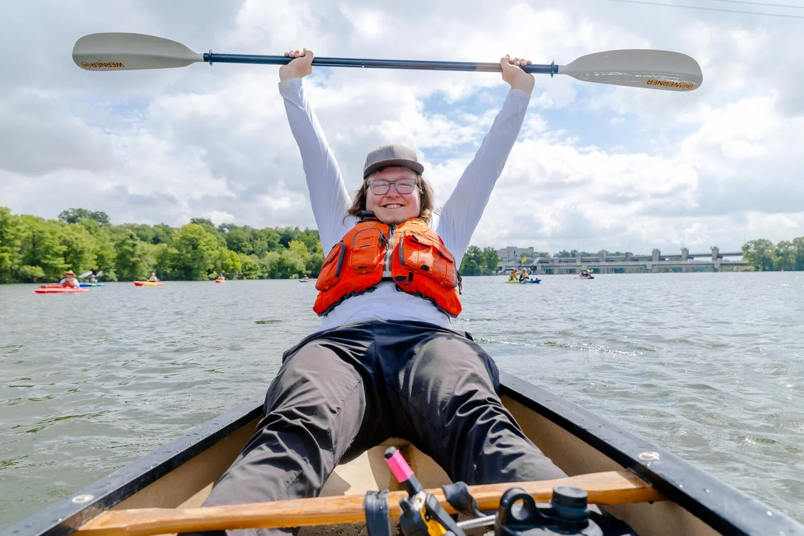 A kayaker joyously holding their oar in the air