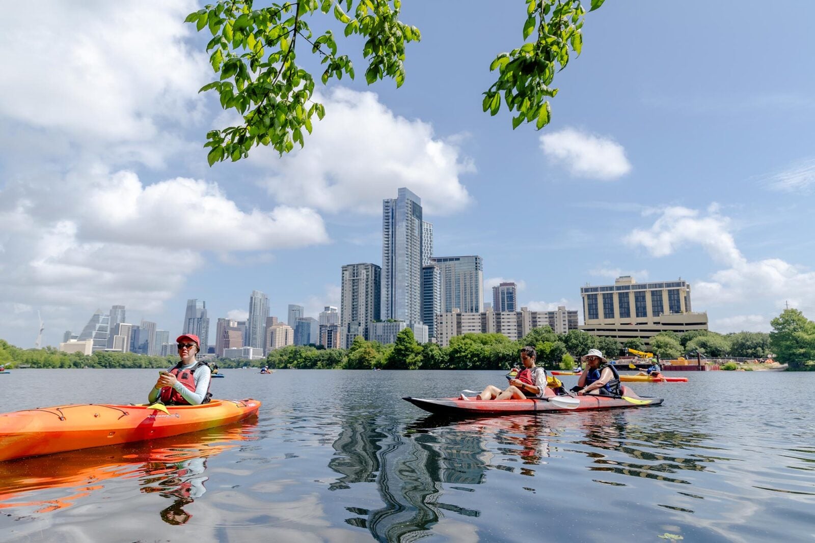 Kayakers on the water in front of the Austin skyline