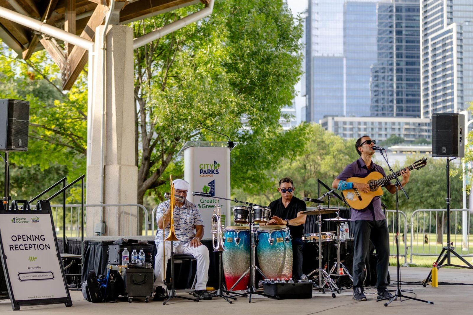 A band performing in a park in front of the Austin city skyline