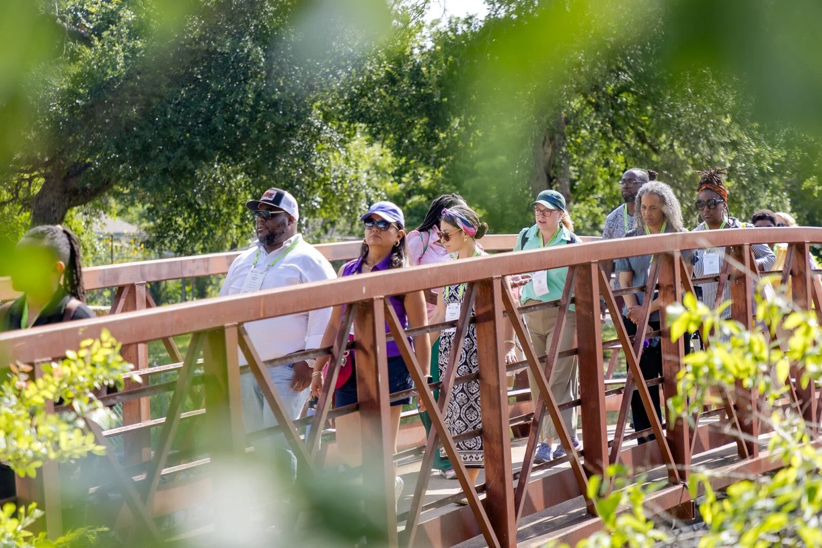 A group of people crossing a foot bridge vignetted by trees