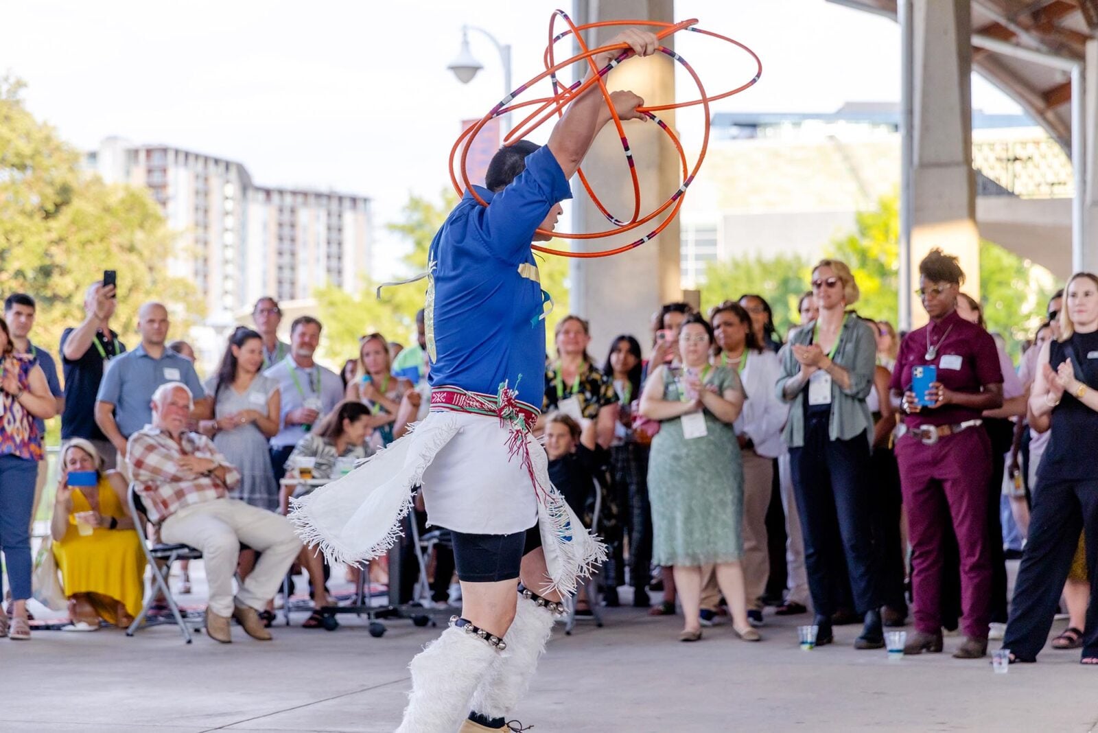 A Native American man doing a traditional hoop dance in front of a crowd