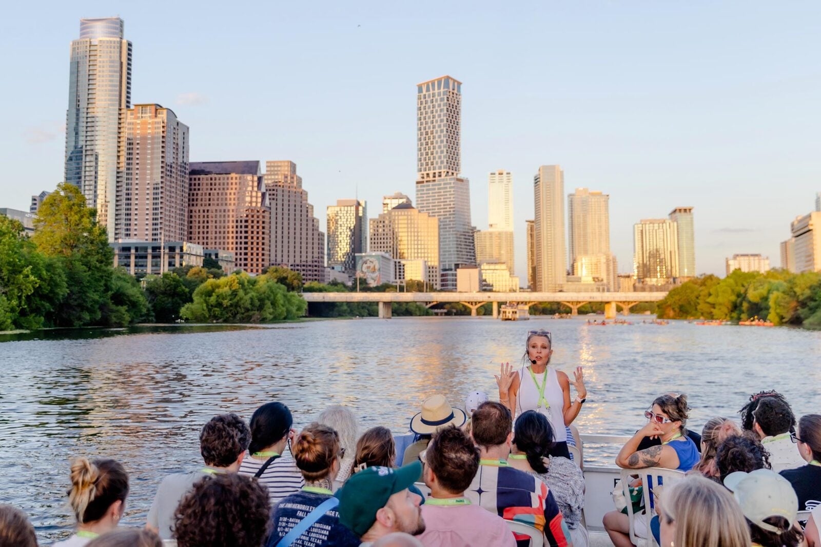 A tour leader on a boat in front of the Austin skyline
