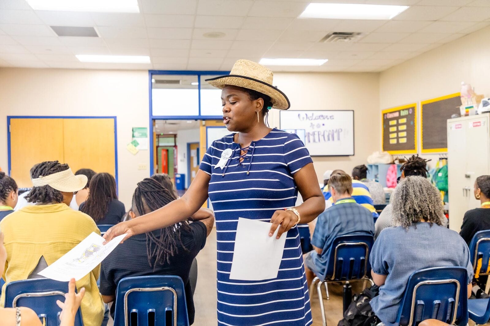 A woman passing papers out in a classroom