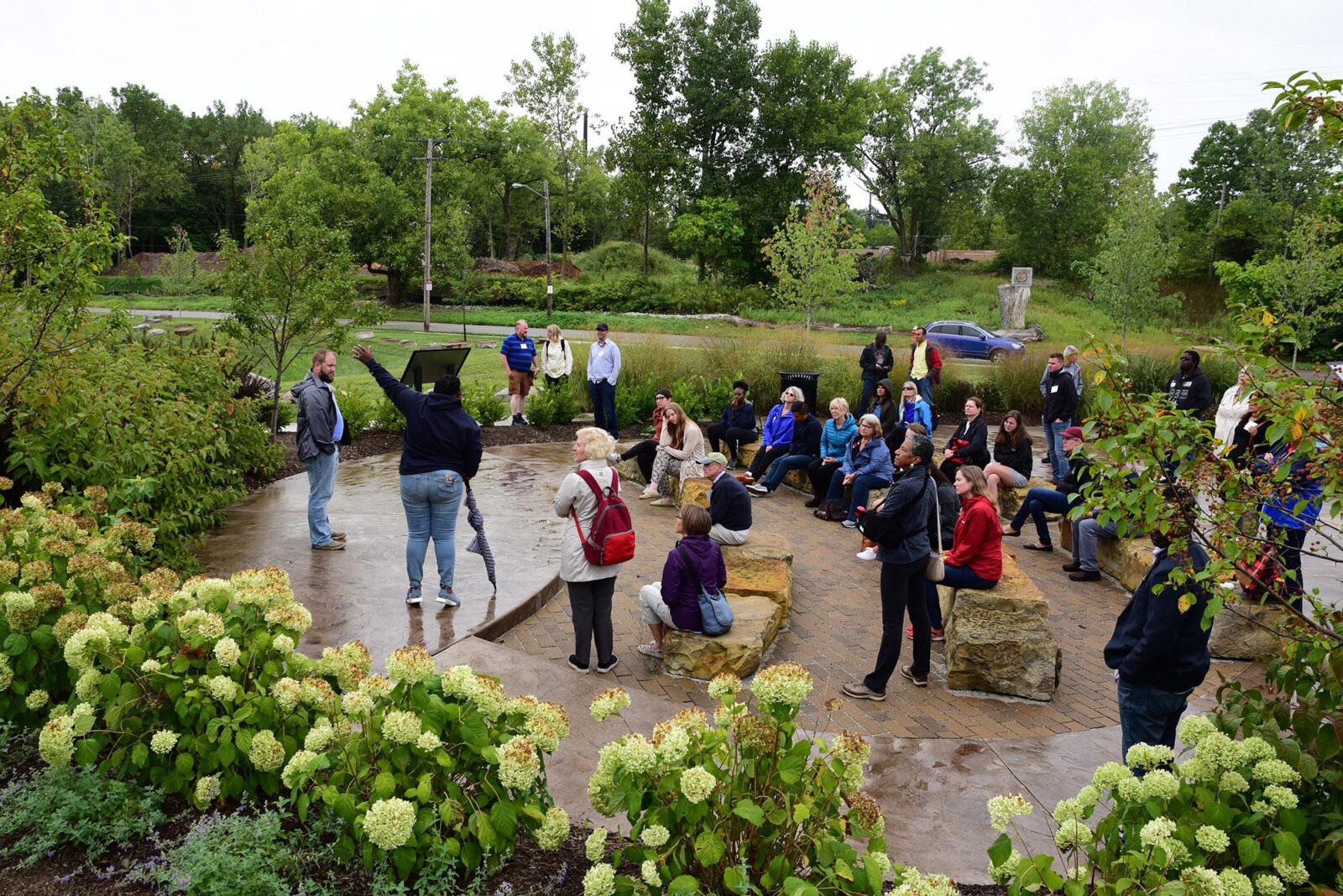 Park Study Tour attendees listening to a tour leader in a park sitting area