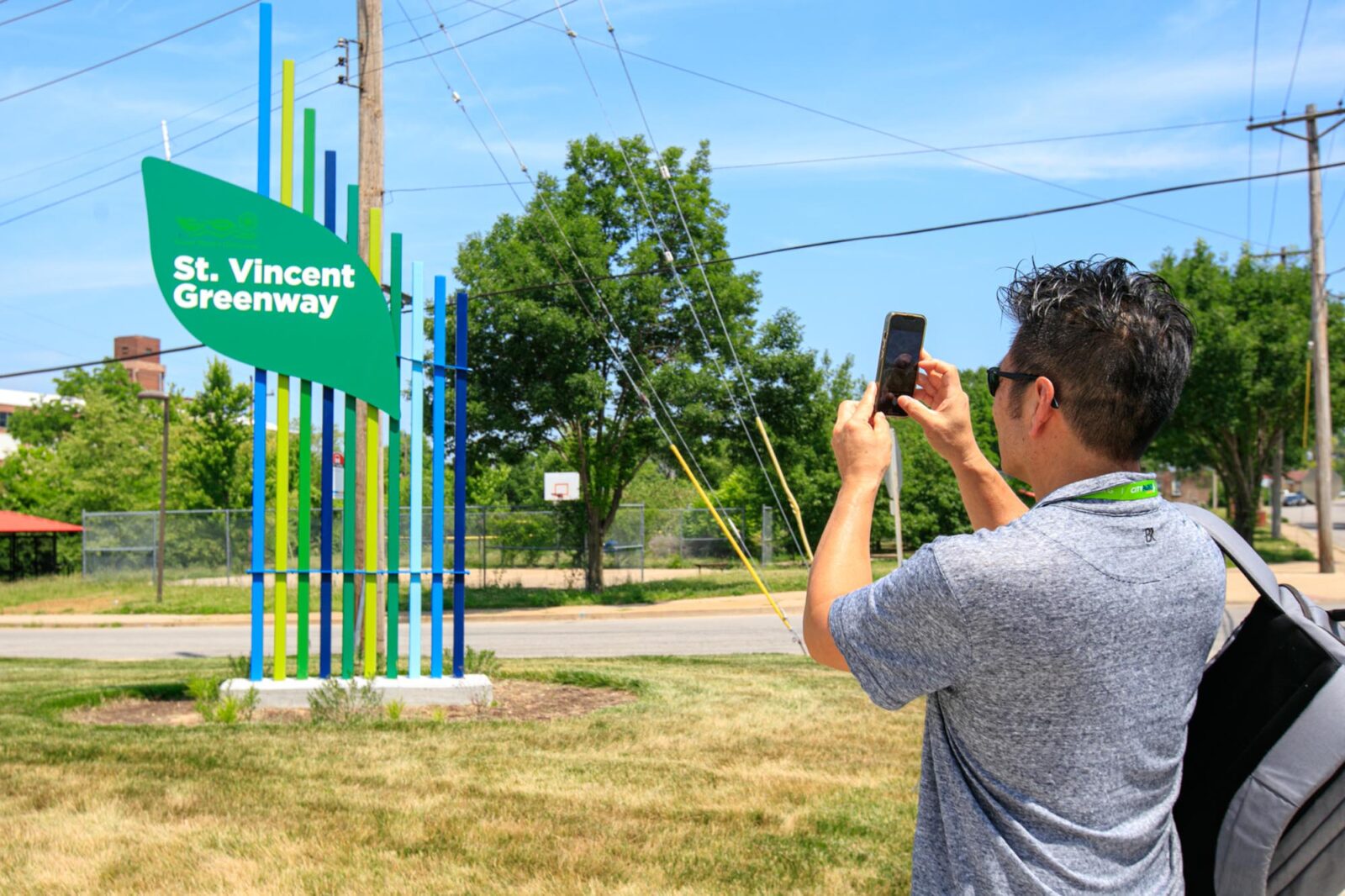 A Park Study Tour attendee taking a mobile picture of the St. Vincent Greenway sign